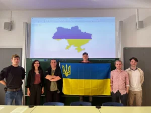 Sunflower Society; Vereinsmitglieder mit Flagge, im Hintergrund der Umriss der Ukraine; in den Nationalfarben