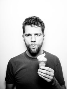 Portraitfoto, Benjamin Fredrich isst ein Eis. Das Bild ist schwarz-weiß gehalten.